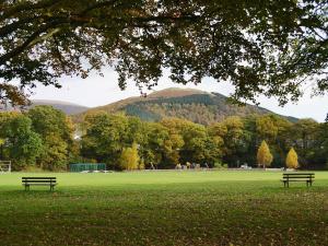 two benches in a park with a mountain in the background at 1 Greta Side Court in Keswick +2 photos