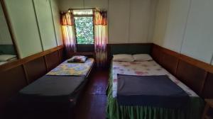 two beds in a small room with a window at Rima Hostel Ruteng in Ruteng