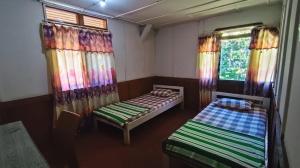 two beds in a room with curtains and windows at Rima Hostel Ruteng in Ruteng