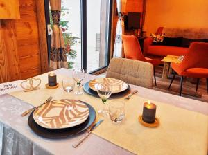 a table with plates and wine glasses on a table at "Le Cabanon cendré" petit chalet cosy au coeur de Gérardmer in Gérardmer