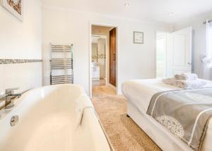 - une salle de bains blanche pourvue d'une baignoire à côté d'un lit dans l'établissement Herons Brook Retreat Lodges, à Narberth