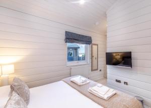 a white room with a bed and a tv at Snainton Luxury Lodges in Ebberston +23 photos