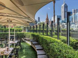 a restaurant with tables and chairs with a view of the city at Quay West Suites Melbourne in Melbourne