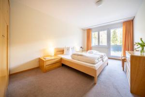a bedroom with a bed and a large window at PL 202 Lichtdurchflutete Wohnung mit grossem Balkon Richtung Scuol in Vulpera