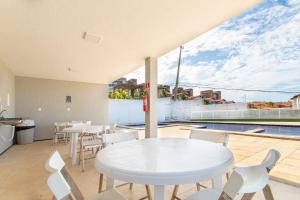a white table and chairs on a patio with a pool at Beach Townhouses - Porto das Dunas By Carpediem in Mangabeira