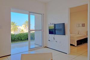 a living room with a sliding glass door with a television at Beach Townhouses - Porto das Dunas By Carpediem in Mangabeira