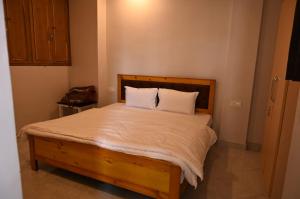 una camera da letto con letto in legno, lenzuola e cuscini bianchi di Mansarovar Heritage Inn ad Almora