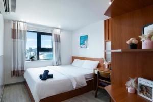 a bedroom with a bed and a desk and a window at Sóng Apartment - Seaside retreat in Da Nang