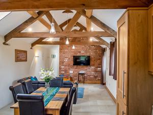 Un comedor con una mesa y sillas y una pared de ladrillos. en Bramble Barn, en Tortworth