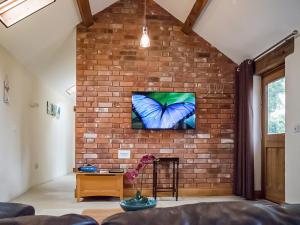 sala de estar con pared de ladrillo y TV en Bramble Barn, en Tortworth 15 fotos más
