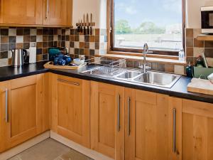 a kitchen with wooden cabinets and a sink and a window at Bramble Barn in Tortworth +16 photos