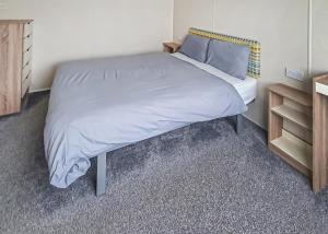 a bedroom with a large bed with a night stand at Ty Gwyn Park in Abergele