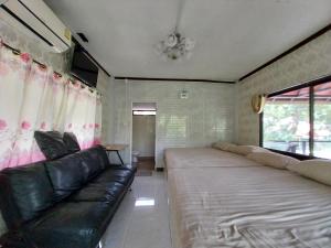 ein Wohnzimmer mit einem Sofa, einem Sofa und einem Fenster in der Unterkunft Bamboo River House Kaengkrachan in Ban Nong Chaeng