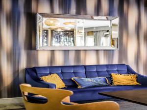 a blue couch in a living room with a mirror at Mercure Milton Keynes Hotel in Milton Keynes