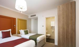 a hotel room with two beds and a bathroom at The Chapter Hotels - London Hyde Park in London