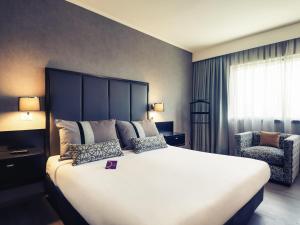 une chambre avec un grand lit et une chaise dans l'établissement Mercure Santiago Centro, à Santiago