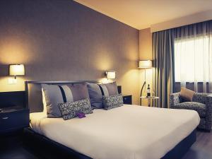 une chambre d'hôtel avec un grand lit et une chaise dans l'établissement Mercure Santiago Centro, à Santiago