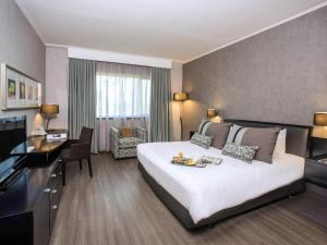 une chambre d'hôtel avec un grand lit et un bureau dans l'établissement Mercure Santiago Centro, à Santiago