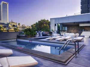 a pool with white chairs and tables on a building at Mercure Santiago Centro in Santiago