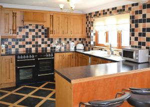 una cocina con armarios de madera y electrodomésticos negros en Aberdwylan Holiday Park, en Abercych