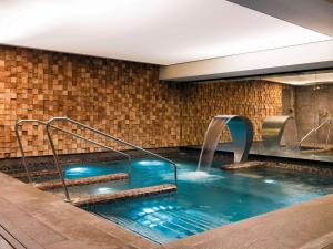 a swimming pool with a waterfall in a building at Balthazar Hotel & Spa Rennes - MGallery Collection in Rennes
