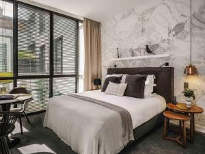 a bedroom with a large bed and a table at Balthazar Hotel & Spa Rennes - MGallery Collection in Rennes +158 photos