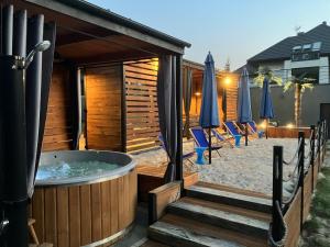 a hot tub with chairs and umbrellas on a patio at domkibajka 
