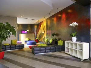 ein Wohnzimmer mit schwarzen Sofas und einer bunten Wand in der Unterkunft Ibis Styles Roma Eur in Rom