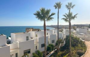 a white building with palm trees in front of the ocean at 4 Bedroom Gorgeous Home In Fuengirola in Las Lagunas Mijas