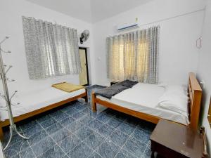 a bedroom with two beds and a table and a window at Guruvayur Agraharam Homestay in Guruvāyūr