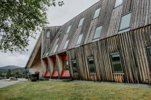 a large wooden building with red chairs in front of it at Preikestolen Hotel & BaseCamp in Jørpeland