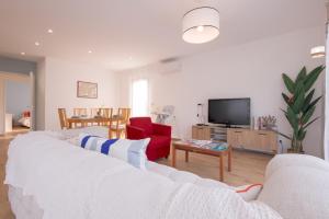 a living room with a white couch and a tv at Villa au coeur de Mézériat in Mézériat
