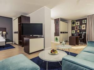 a living room with a couch and a tv at Mercure Hotel Koeln Belfortstrasse in Cologne