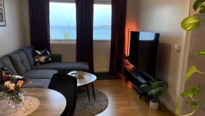 a living room with a couch and a flat screen tv at Sjelefred - Ocean Suite in Sortland