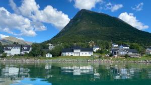 a village by the water with a mountain in the background at Sjelefred - Ocean Suite in Sortland