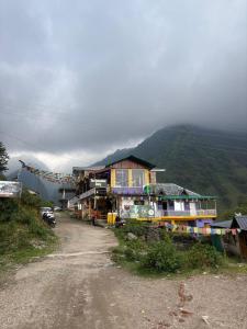a dirt road next to a building on a mountain at The Backpacker Storey in Kangra +10 photos