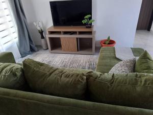 a living room with a green couch and a television at T & M Apartments in Ndola