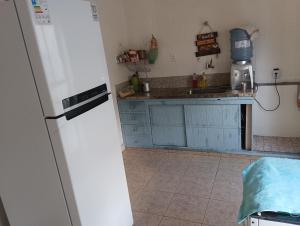 a kitchen with blue cabinets and a white refrigerator at Quarto 01 in Montes Claros