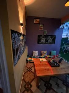 a dining room with a wooden table and purple walls at The Backpacker Storey in Kangra