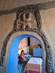 una mujer está sentada en una cama en una habitación en Gîte Palma Eagle Ziz Canyon, en Er Rachidia