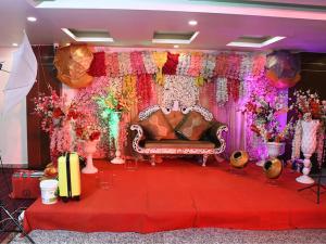 a stage with a couch and flowers on it at Aalcajars Inn in Patna
