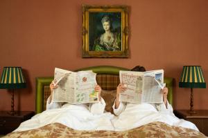two people laying in bed reading the newspapers at Landgoed Duin & Kruidberg in Santpoort-Noord