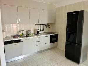 a kitchen with white cabinets and a black refrigerator at Cielo Dorado in Santiago del Teide