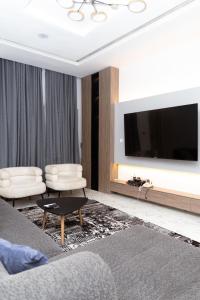 a living room with a tv and a couch and chairs at Luxury 3BR Apt w balcony view in Chevron, Lekki in Lekki +11 photos