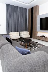 a living room with a couch and a tv at Luxury 3BR Apt w balcony view in Chevron, Lekki in Lekki