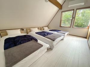 two beds in a room with two windows at コテージソラ まるっと一棟貸切り別荘 in Nasu-yumoto