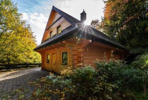 une cabane en rondins avec le soleil brillant sur le toit dans l'établissement Chata na Skarpie - SPA i widok na Skrzyczne, à Szczyrk