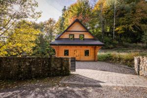 une maison avec un toit noir et un mur en pierre dans l'établissement Chata na Skarpie - SPA i widok na Skrzyczne, à Szczyrk