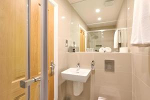 a white bathroom with a sink and a mirror at The Chapter Hotels - London Hyde Park in London +21 photos
