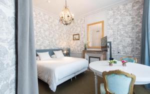a hotel room with a bed, chair, table and lamps at Hôtel La Monnaie Art & Spa in La Rochelle